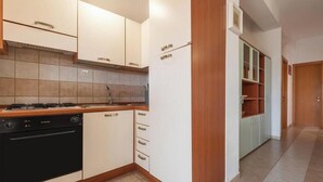 A modern kitchen with white cabinets, a black oven, and a wooden countertop.