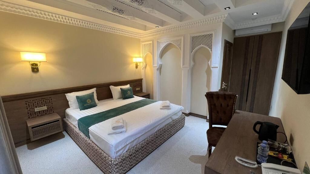 A hotel room with a bed, bedside tables, a desk, and a chair.