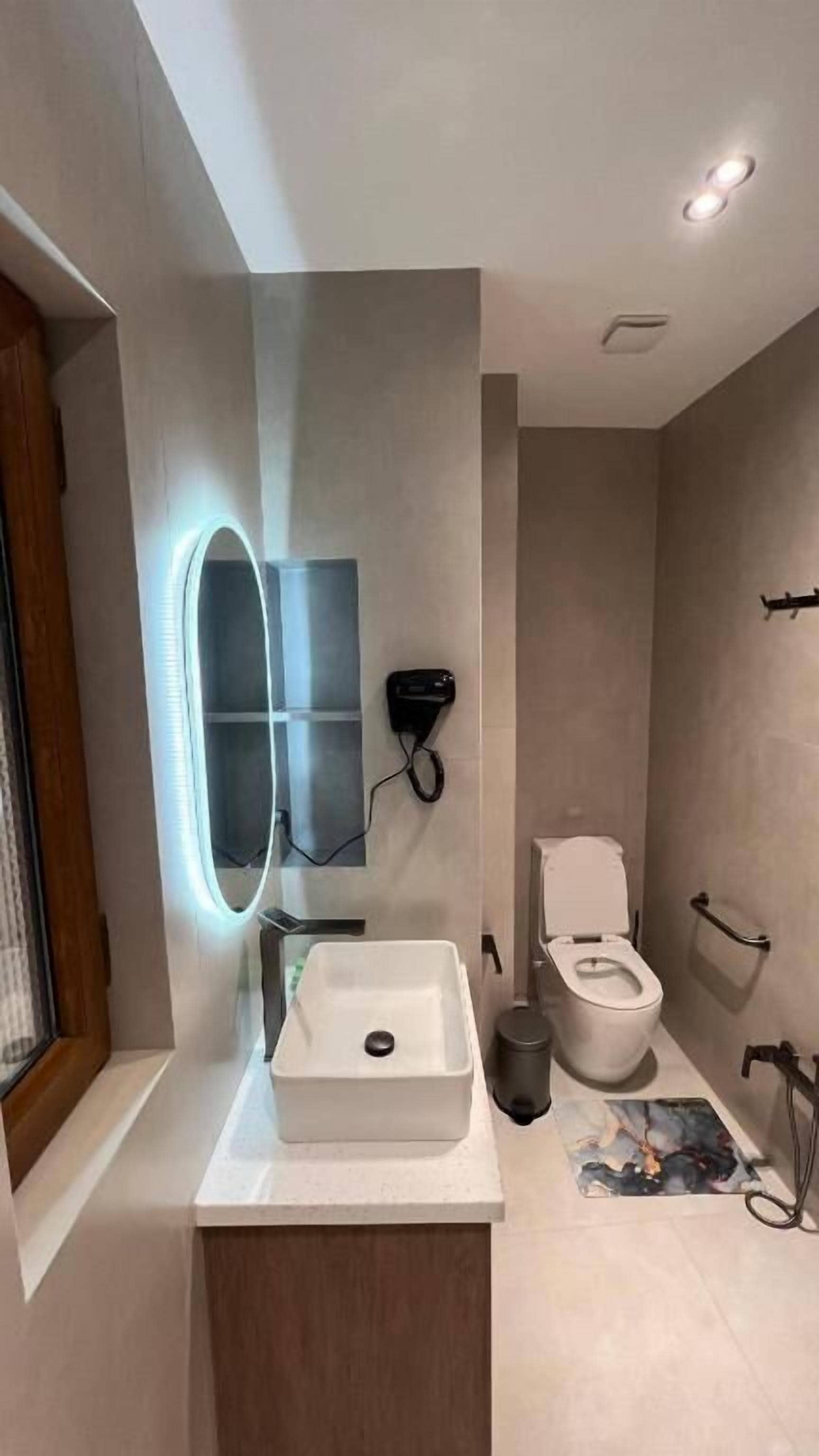 Un bany modern amb un lavabo integrat, un mirall fixat a la paret i un vàter.