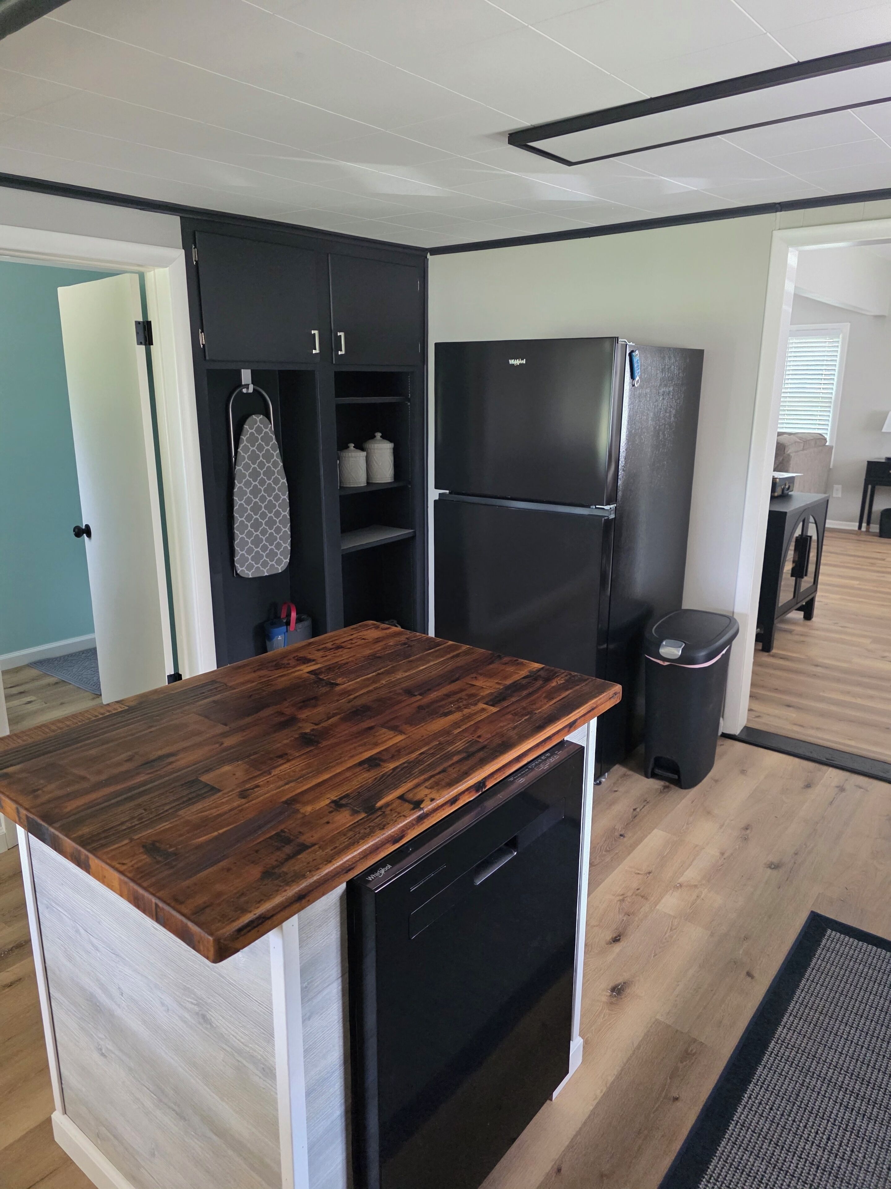 A kitchen with a wooden countertop, black appliances, and a trash bin.