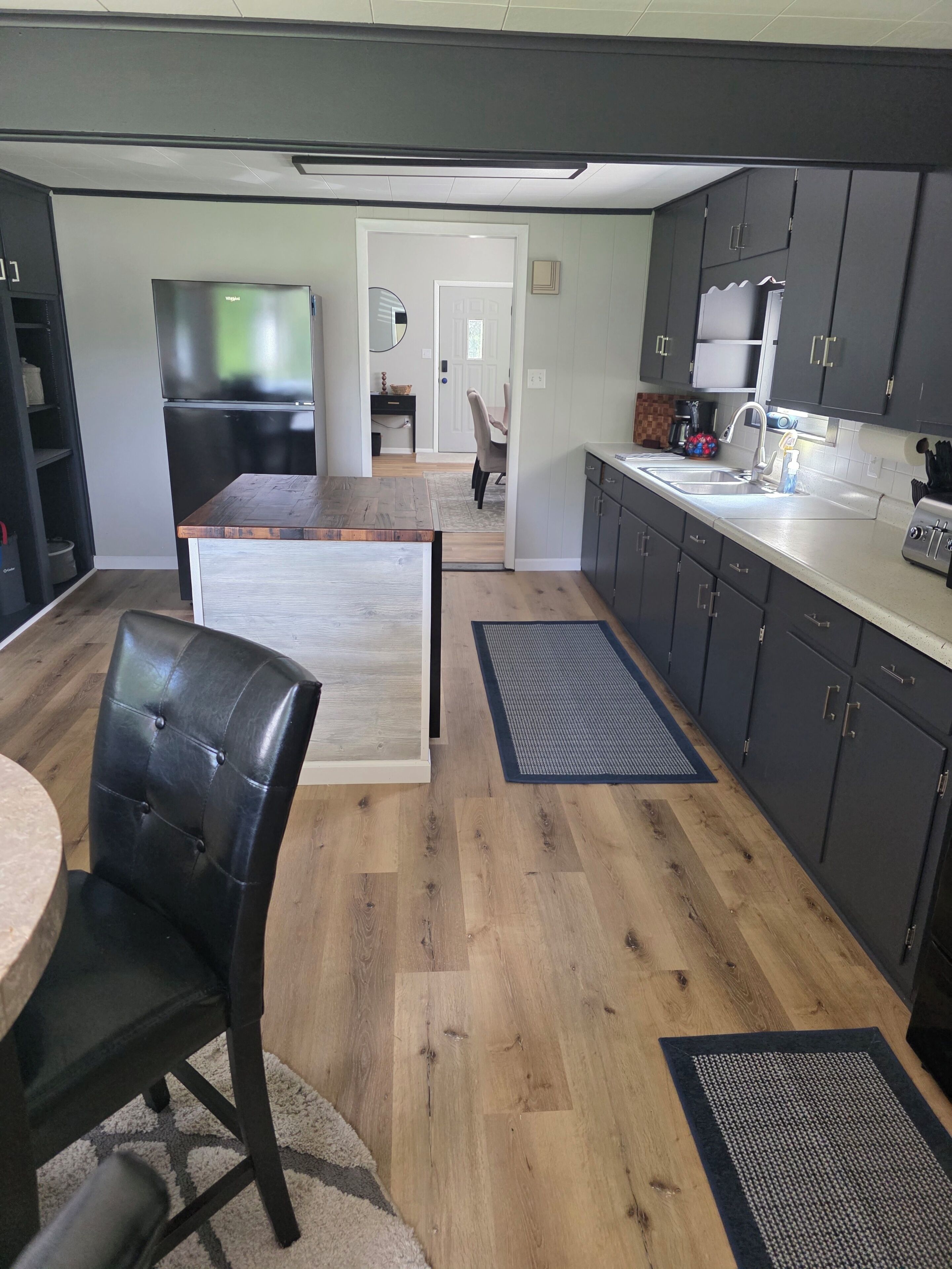 Une cuisine moderne avec des meubles de couleur sombre, une table à manger en bois et une chaise en cuir noir.