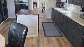A modern kitchen with dark cabinets, a wooden dining table, and a black leather chair.