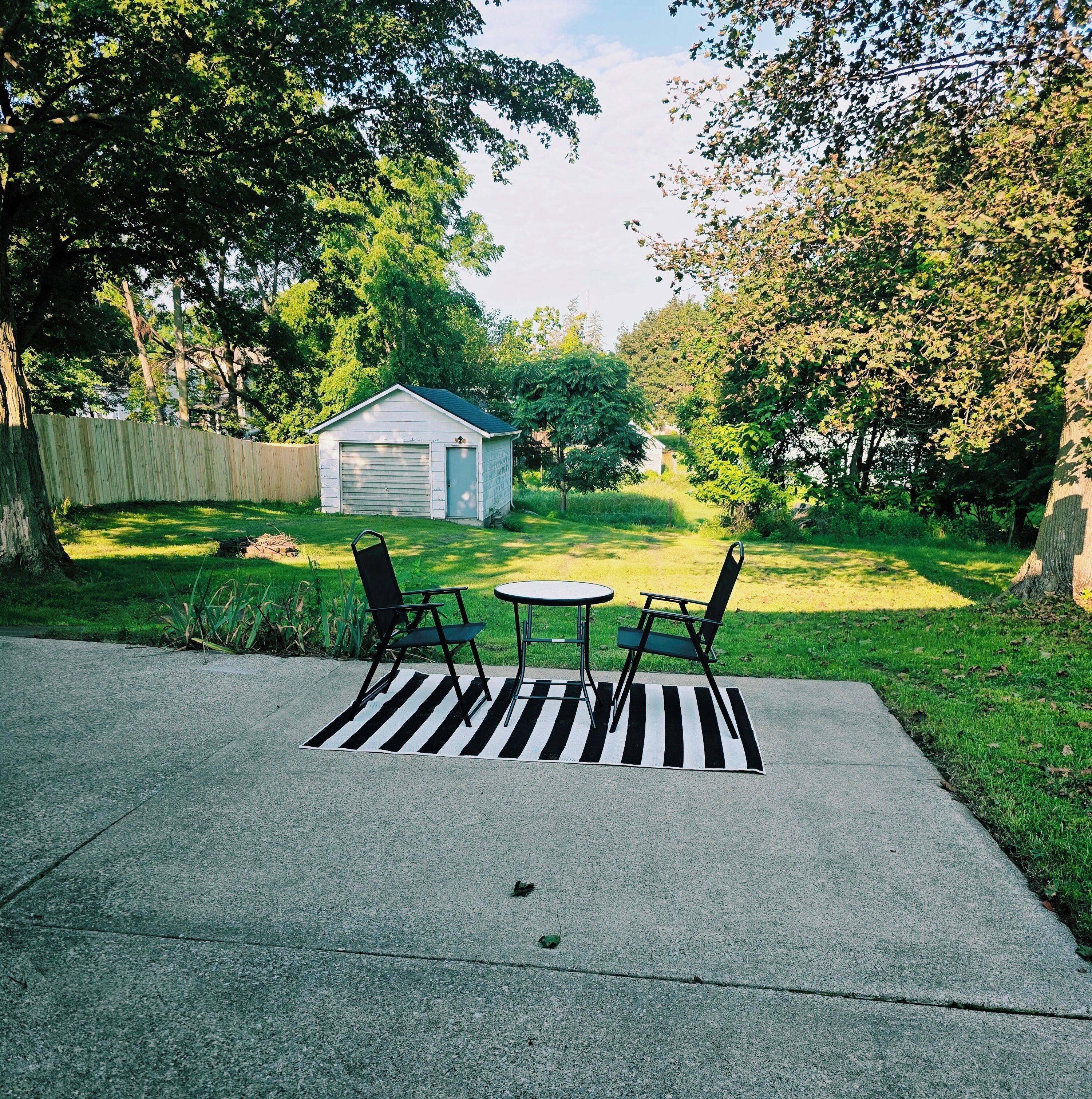 Un jardin avec un espace patio, un abri de jardin et une pelouse.