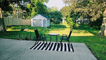A backyard with a patio area, a shed, and a lawn.