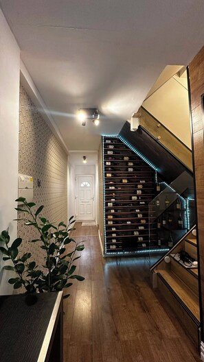 A modern interior with a staircase, wooden flooring, and a wall with a geometric pattern. - Modern Home in Surrey Quays/ Canada Water (London)