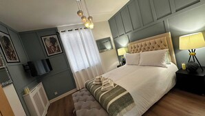Een hotelkamer met een groot bed, bedlampen, een flatscreen televisie en een raam met gordijnen.