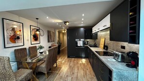 Een moderne keuken met donkere kastjes, een ingebouwde oven en een aanrecht met een waterkoker.