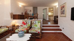 En stue med en sofa, et sofabord med en vase og en trappe, der fører til en etage ovenpå.