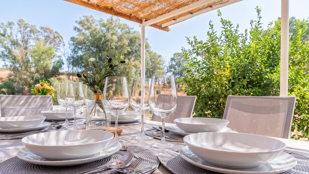 An outdoor dining setup with white plates, clear glasses, and a woven table mat. - Cubo's Casa Alaya & Oasis Pool / Private pool / Air conditioning / BBQ / Free Wi-Fi (Coín)
