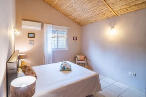 Ein Schlafzimmer mit Bett, Stuhl, Fenster und Wandleuchten.