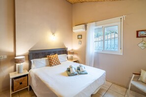 A hotel room with a bed, bedside lamps, a nightstand, a window with curtains, and a wall-mounted air conditioning unit. - Cubo's Casa Alaya & Oasis Pool / Private pool / Air conditioning / BBQ / Free Wi-Fi (Coín)