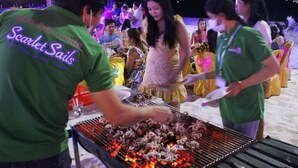 A group of people gathered around a barbecue grill outdoors at night. - Scarlet Sails Resort Koh Rong (Koh Rong)