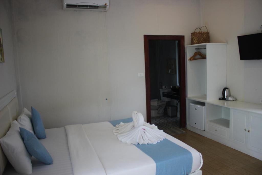 A hotel room with a bed, a wardrobe, a television, and a bathroom visible through an open door.