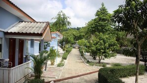 A pathway leading to a row of houses with a tiled roof, surrounded by greenery and trees. - Scarlet Sails Resort Koh Rong (Koh Rong)