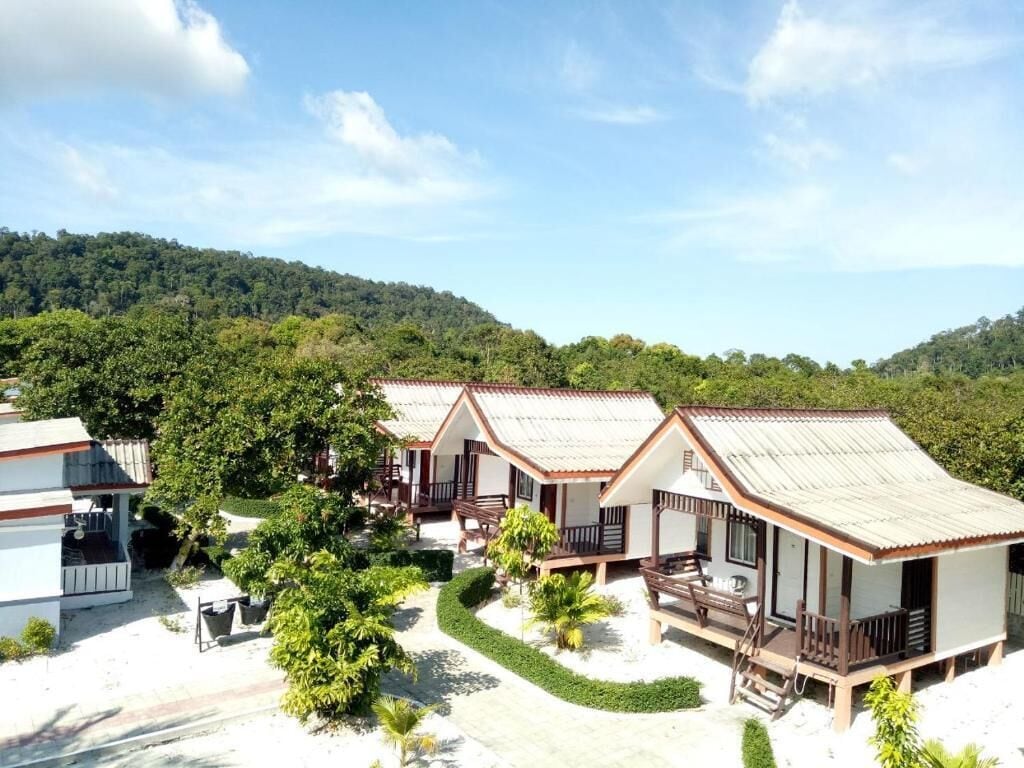 Cabañas estilo bungalow con techo plano, rodeadas de vegetación y un paisaje montañoso.