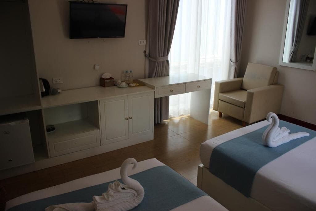 Hotelkamer met een bed, een bureau, een stoel, een televisie en een raam met gordijnen.
