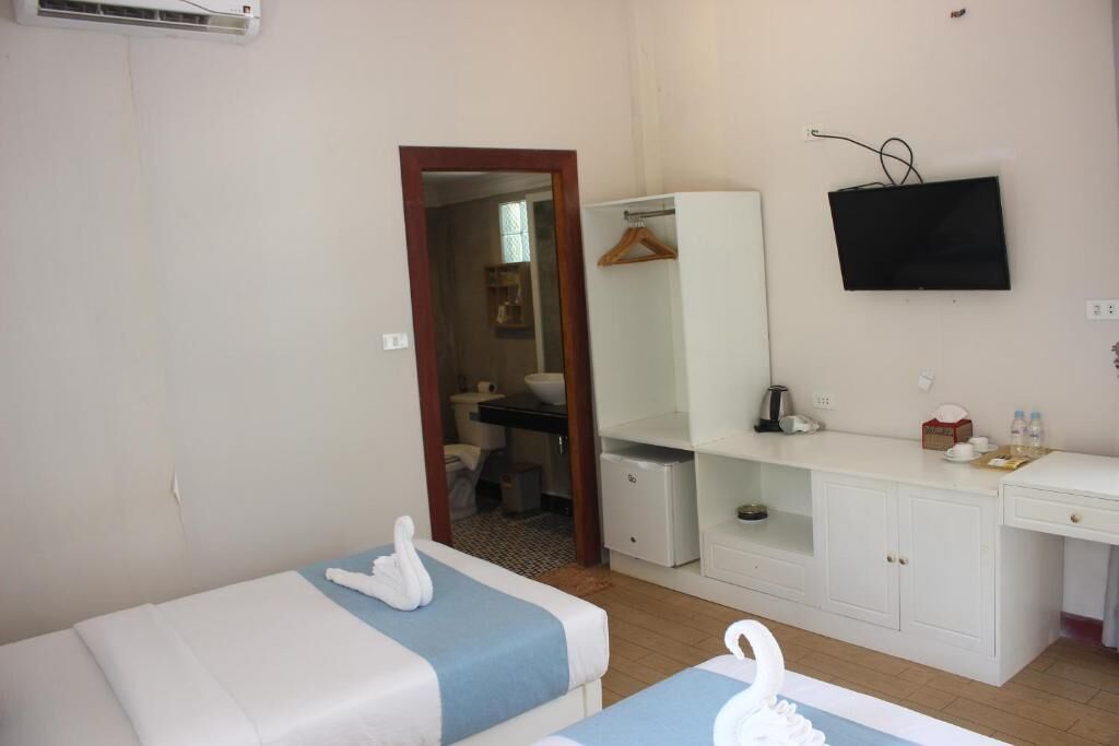 A hotel room with two beds, a TV, a wardrobe, and a desk.