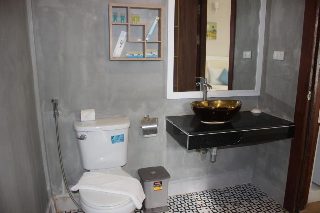 A bathroom with a toilet, sink, and mirror.