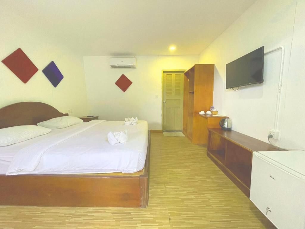 Una habitación de hotel con cama, televisor, armario y escritorio con tetera.