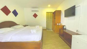 Una habitación de hotel con cama, televisor, armario y escritorio con tetera.
