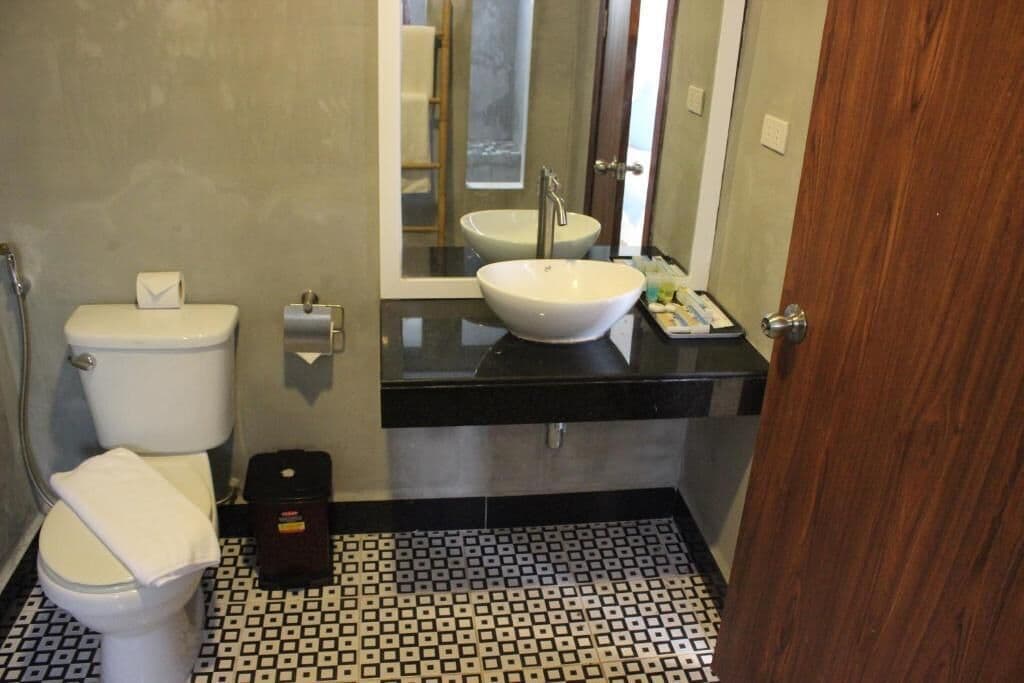 A bathroom with a toilet, a sink, and a mirror.