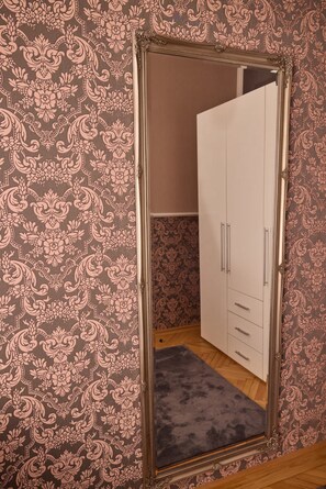 A room with patterned wallpaper, a wardrobe with multiple doors, and a mirror. - Sophie's Place Augarten - Imperial Lifestyle Apartments (Wien)