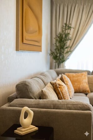 Ein Wohnzimmer mit einer Couch, Kissen, einem kleinen Tisch mit einer Dekoration und einer Pflanze.