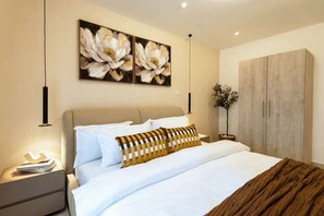 Ein modernes Schlafzimmer mit Bett, Nachttischen, einem Kleiderschrank und Bildern an der Wand.