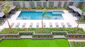 Ein rechteckiger Pool mit mehreren Liegestühlen und einer kleinen Palme.
