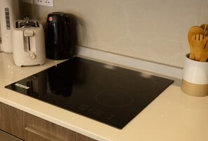Eine Küche mit einer schwarzen Induktionskochplatte, einem Toaster und einer Kaffeemaschine auf der Arbeitsfläche.