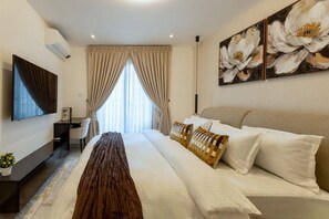 A hotel room with a bed, a TV, a desk, and a large window with curtains. - Luxe 1BR Apt at TheBantree, Airport (Accra)