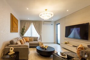 Ein modernes Wohnzimmer mit einer Couch, einem Couchtisch und einem an der Wand befestigten Flachbildfernseher.
