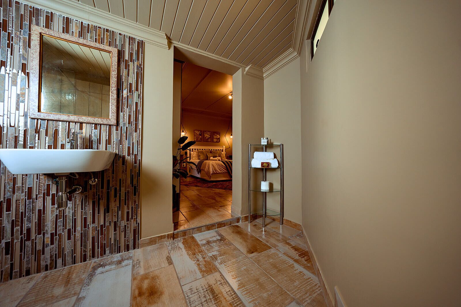 Un bagno con parete decorata a mosaico, lavandino e zona doccia.