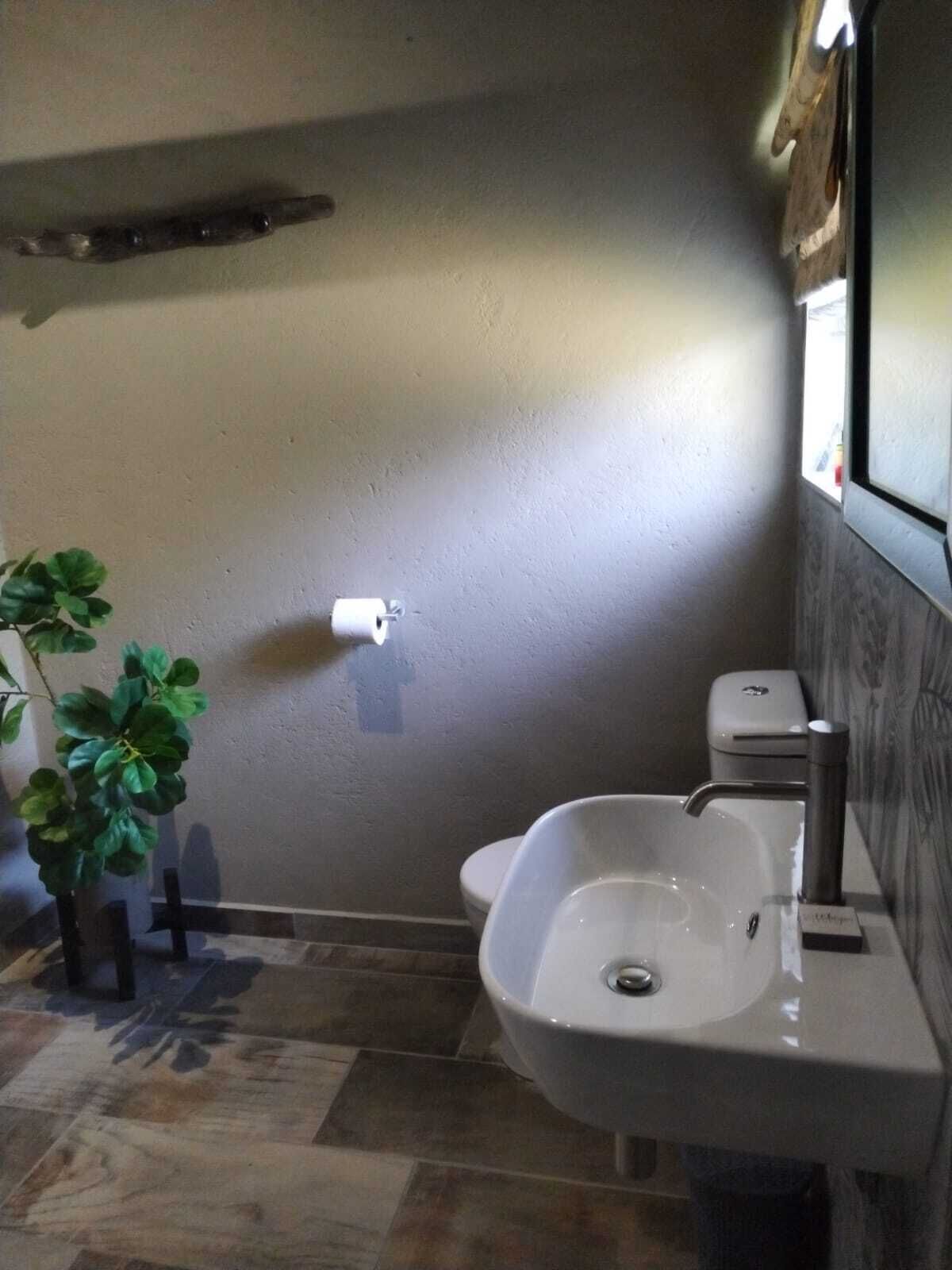 Un baño con lavamanos, inodoro y una planta.