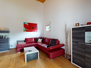 A modern living room with a red leather sofa, a white coffee table, and a wooden floor. - Soras Demarmels Appartement/Fewo, Dusche, WC, 2 Schlafräume by Interhome (Savognin)