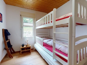 A room with a bunk bed, a small table with a lamp, and a window. - Soras Demarmels Appartement/Fewo, Dusche, WC, 2 Schlafräume by Interhome (Savognin)
