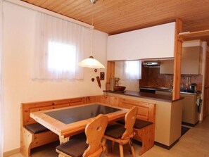 Kompakti keittiö, jossa on keskeinen saareke, puiset huonekalut ja ikkuna, jossa on verhot.
