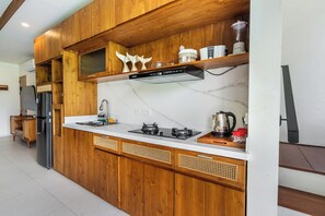 Een moderne keuken met houten kastjes, een ingebouwde magnetron en een gasfornuis.