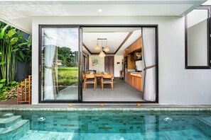 A modern house with a glass door leading to a dining area and kitchen. - 2-bedroom house in peaceful Gianyar with private pool and natural views (Gianyar)