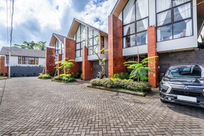 A modern building with a brick facade, large windows, and a paved driveway. - 2-bedroom house in peaceful Gianyar with private pool and natural views (Gianyar)