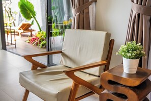 Een moderne lounge fauteuil met een bekleed zitvlak en rugleuning, geplaatst naast een houten bijzettafeltje met een bloempot.