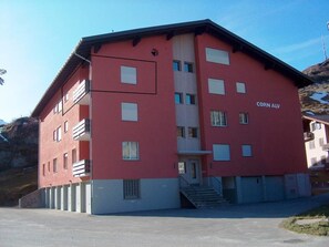 Ein rotes Gebäude mit vielen Fenstern und einem Schild, auf dem 'Corn ALV' steht.