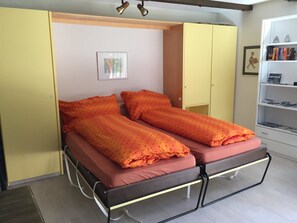 A bed with two pillows and a mattress, a bedside table, a wardrobe, and a bookshelf with books. - Corn Alv 13 Appartement/Fewo, Dusche oder Bad, WC, 1 Schlafraum by Interhome (Bivio)