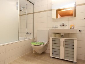 Ein Badezimmer mit Dusche, Toilette und einem Schrank mit Schubladen.