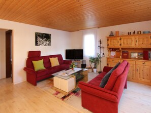 Ein Wohnzimmer mit einem roten Sofa, einem Fernseher und Holzausbau.