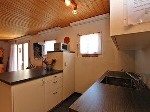 Eine kleine Küche mit Holzbalkendecke, einer Mikrowelle, einem Kühlschrank und einem Waschbecken.