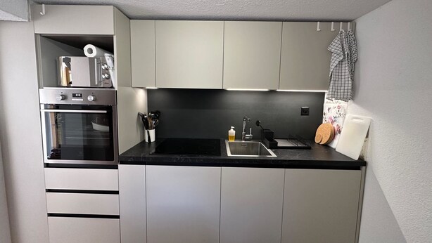 A compact kitchen with a built-in oven, a sink, and a countertop. - Jonnys Paradisli Appartement/Fewo, Dusche und Bad, WC, 1 Schlafraum by Interhome (Cunter)