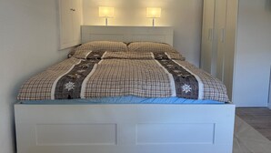 A single-bed room with a white headboard, two bedside lamps, and a wardrobe with a door. - Jonnys Paradisli Appartement/Fewo, Dusche und Bad, WC, 1 Schlafraum by Interhome (Cunter)