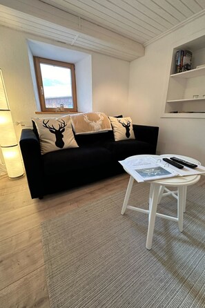 Ein gemütliches Wohnzimmer mit einer schwarzen Couch, einem weißen Couchtisch und einem Fenster mit Blick.