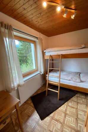 Kerrossängyllä varustettu huone, jossa on ikkuna, puinen katto ja pieni pöytä.
